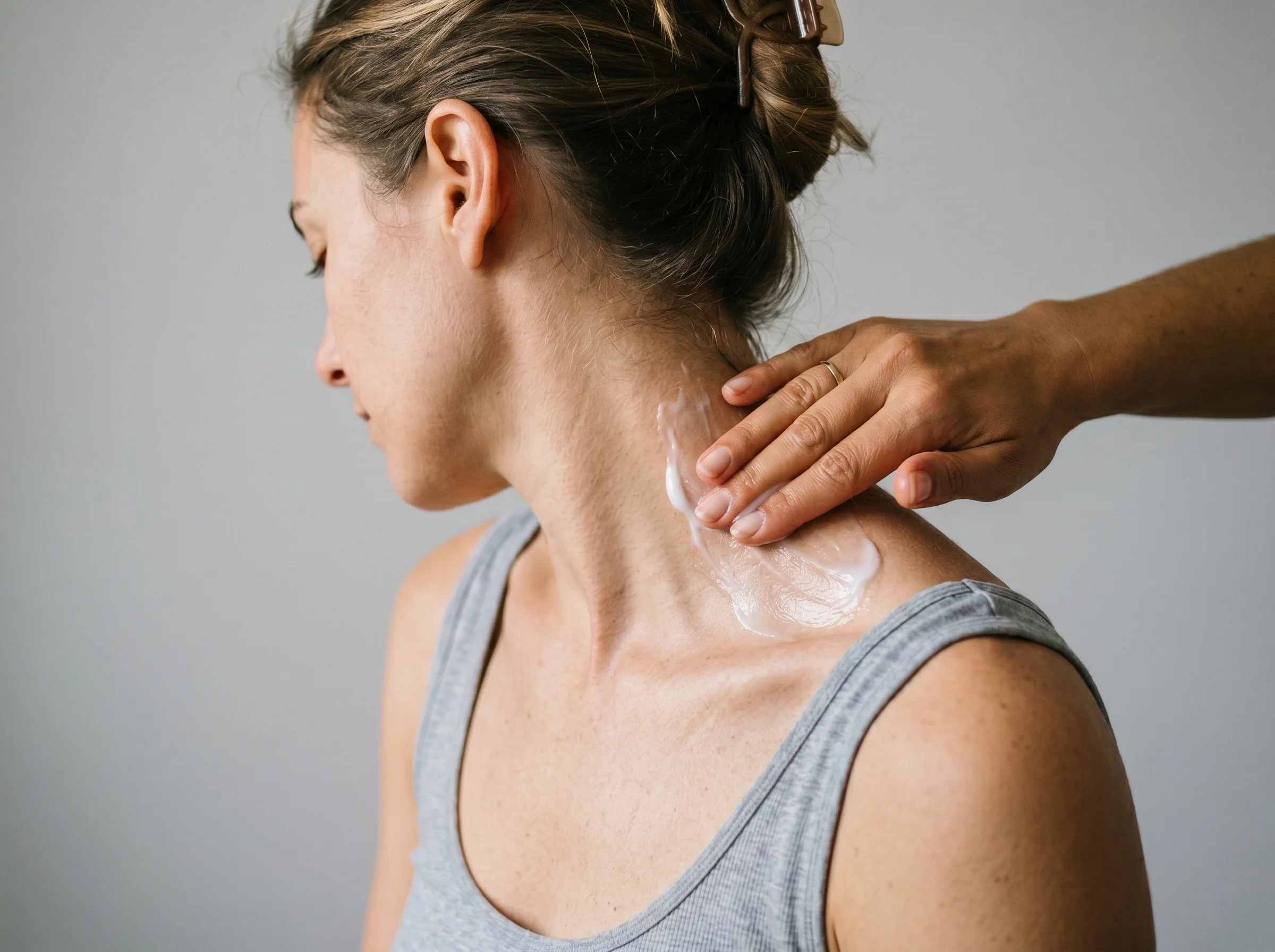 aplicando crema antiinflamatoria en el trapecio espalda