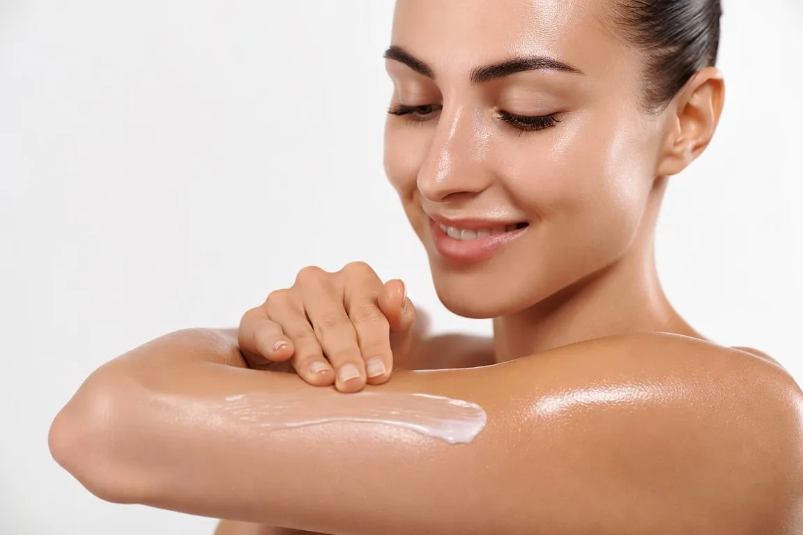 mujer aplicando crema hidratante brazo piel suave cuidado